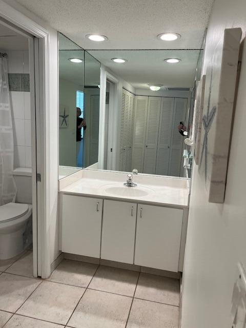 bathroom with tile patterned floors, vanity, a textured ceiling, and toilet