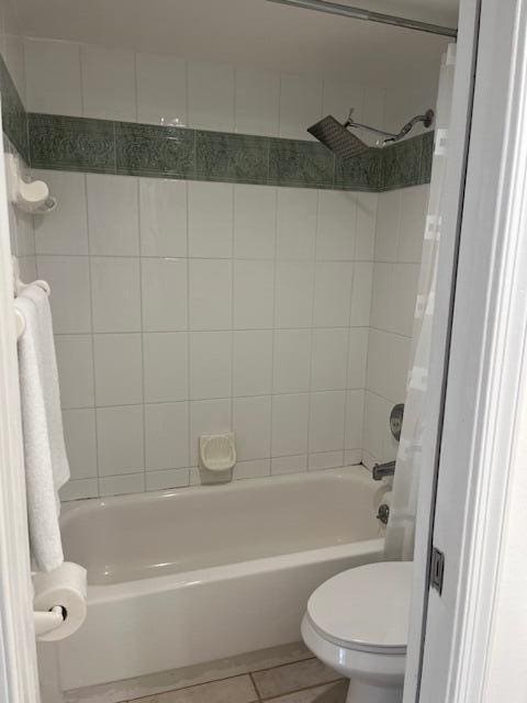 bathroom featuring tile patterned floors, tiled shower / bath, and toilet