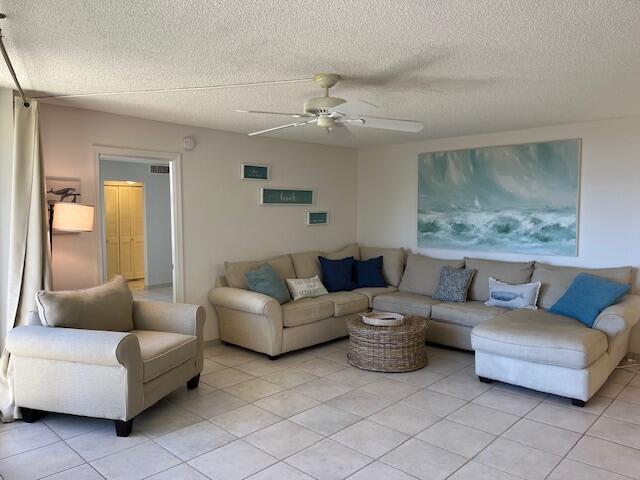 tiled living room with a textured ceiling and ceiling fan