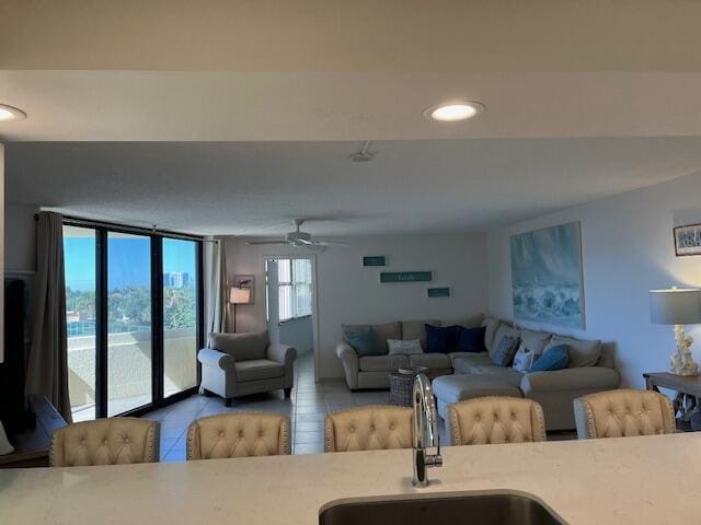 living room with ceiling fan, a water view, and sink