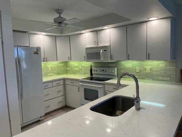 kitchen featuring ceiling fan, sink, white appliances, decorative backsplash, and light tile patterned floors