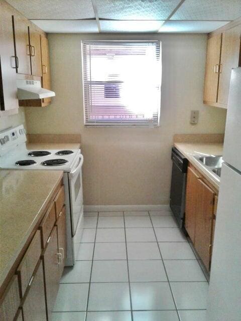 kitchen featuring sink, light tile patterned floors, and white appliances