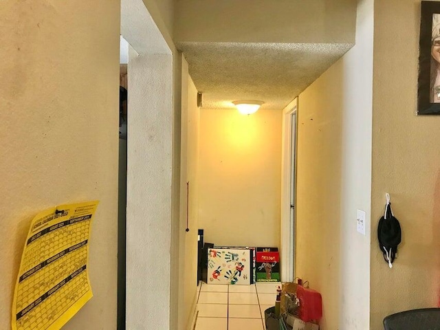 hallway with a textured ceiling and light tile patterned flooring