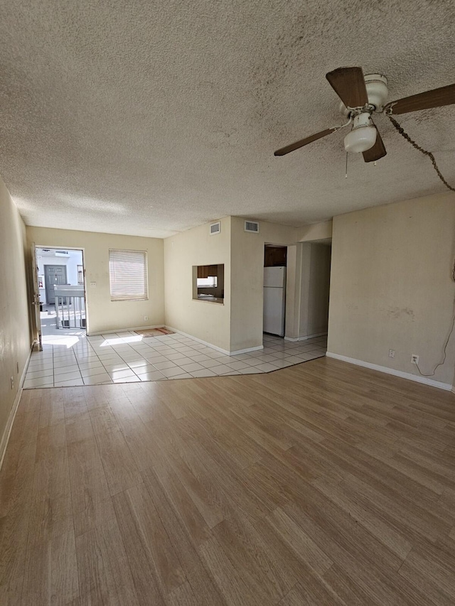 unfurnished living room with a textured ceiling, wood finished floors, and visible vents