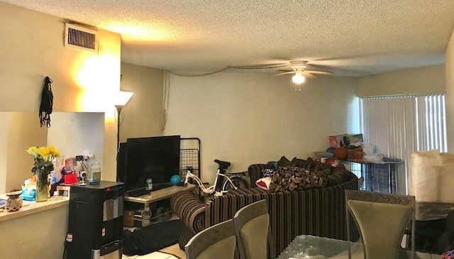 living room featuring ceiling fan and a textured ceiling