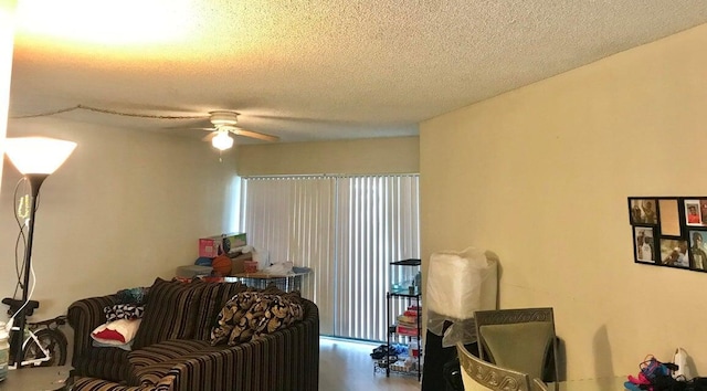 living room featuring ceiling fan and a textured ceiling