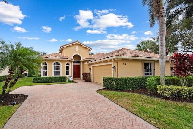 mediterranean / spanish-style home with a garage and a front lawn