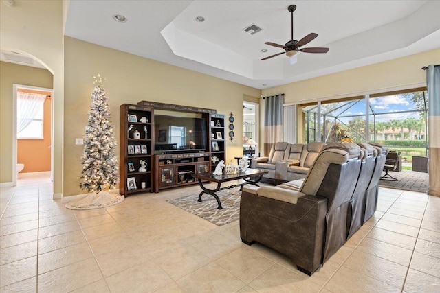 tiled living room featuring a tray ceiling and ceiling fan