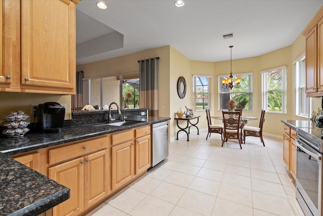 kitchen with dark stone counters, an inviting chandelier, hanging light fixtures, appliances with stainless steel finishes, and light tile patterned flooring