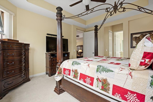 bedroom with ceiling fan, light carpet, and a tray ceiling