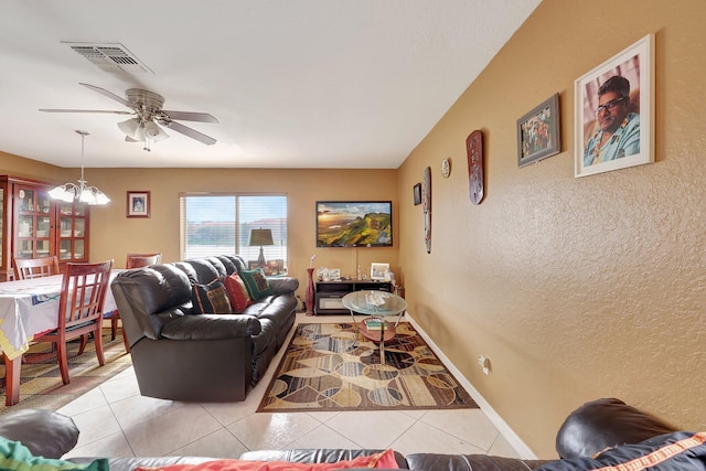 living room featuring ceiling fan with notable chandelier and light tile patterned floors