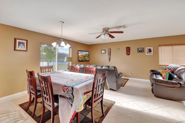 tiled dining room with ceiling fan with notable chandelier