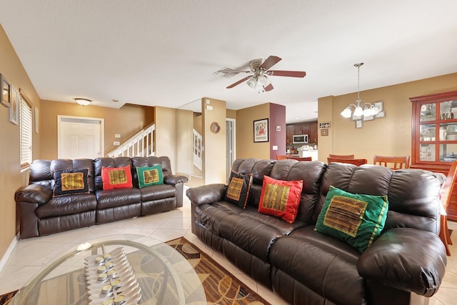 tiled living room featuring ceiling fan with notable chandelier