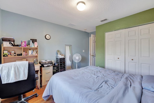 bedroom featuring a textured ceiling, light hardwood / wood-style flooring, and a closet