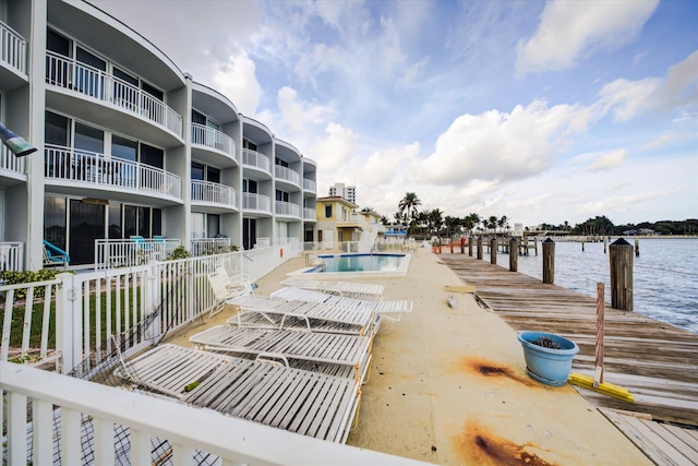 view of swimming pool featuring a water view and a dock