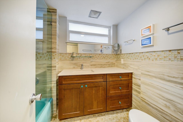 full bathroom featuring tile walls, vanity, enclosed tub / shower combo, and toilet