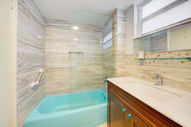 bathroom featuring vanity, tiled shower / bath combo, decorative backsplash, and tile walls