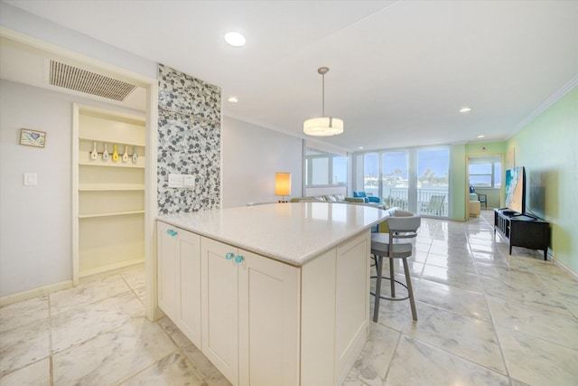 kitchen with crown molding, a kitchen breakfast bar, hanging light fixtures, and white cabinets