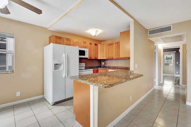 kitchen with white appliances, decorative backsplash, light tile patterned floors, light stone counters, and kitchen peninsula