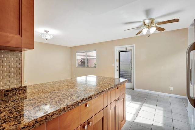 kitchen with ceiling fan, dark stone countertops, and light tile patterned floors