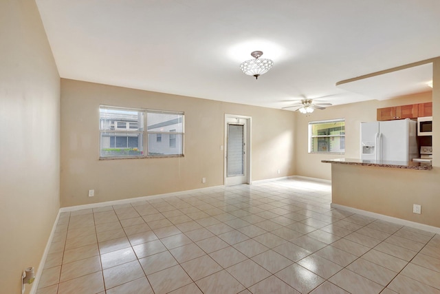 tiled empty room with plenty of natural light and ceiling fan