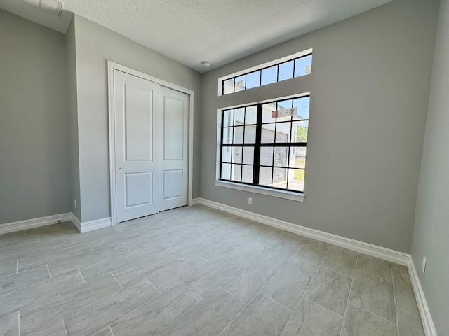 13200 SE US Highway 441, Okeechobee, FL 34974 - unfurnished bedroom with a textured ceiling, a closet, and baseboards