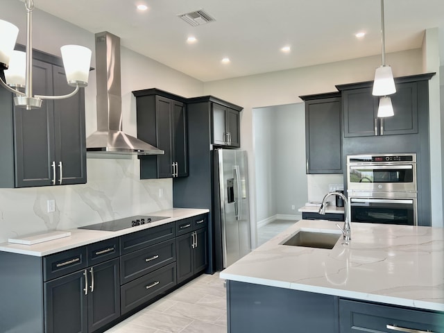 kitchen with sink, stainless steel appliances, light stone counters, and wall chimney range hood