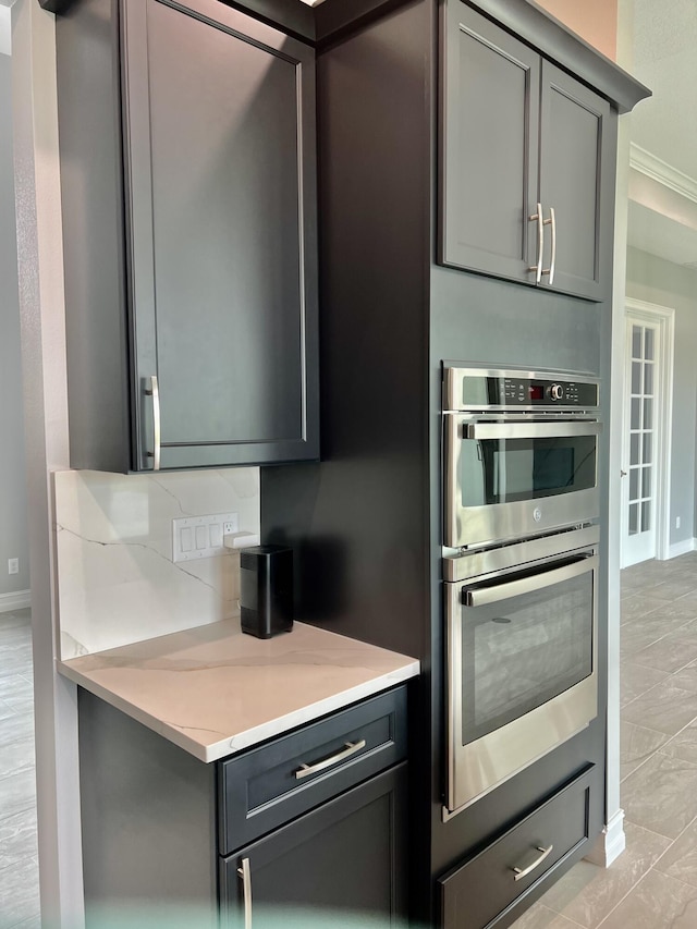 kitchen featuring gray cabinetry, ornamental molding, and double oven