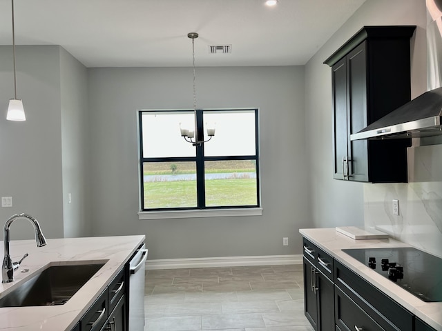 kitchen featuring sink, wall chimney exhaust hood, black electric cooktop, decorative light fixtures, and light stone counters