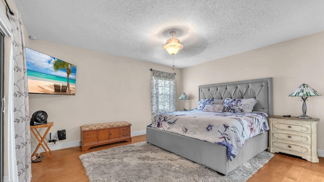 bedroom featuring ceiling fan, light wood-type flooring, and a textured ceiling