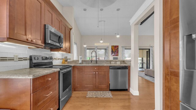 kitchen featuring sink, light wood-type flooring, tasteful backsplash, decorative light fixtures, and stainless steel appliances