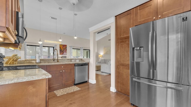 kitchen featuring hanging light fixtures, stainless steel appliances, light stone counters, light hardwood / wood-style floors, and lofted ceiling