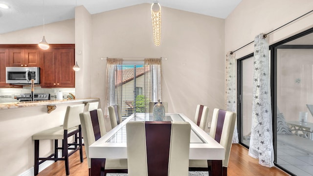 dining room with vaulted ceiling and light wood-type flooring