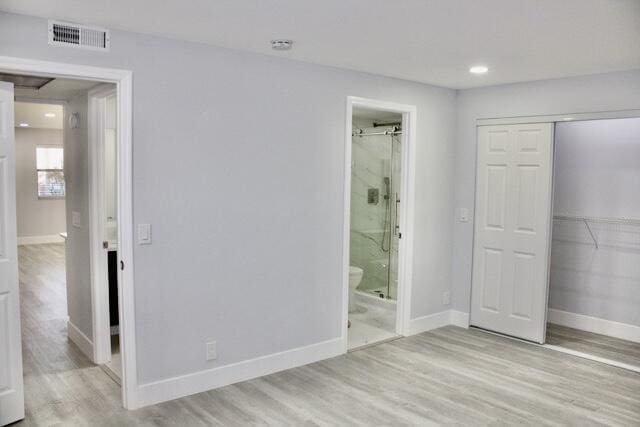 unfurnished bedroom with light hardwood / wood-style floors, ensuite bath, and a closet