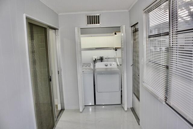 laundry area with washer and clothes dryer and ornamental molding