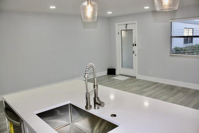 interior space featuring dishwashing machine, hardwood / wood-style floors, decorative light fixtures, and sink