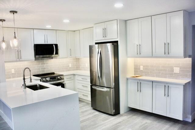 kitchen with sink, white cabinets, stainless steel appliances, and decorative light fixtures