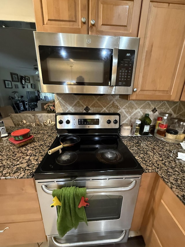 kitchen featuring tasteful backsplash, dark stone countertops, and stainless steel appliances