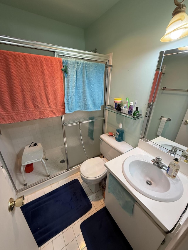 bathroom featuring tile patterned flooring, vanity, toilet, and a shower with door