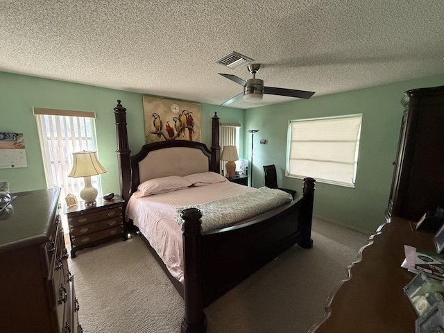 bedroom with ceiling fan, light colored carpet, and a textured ceiling