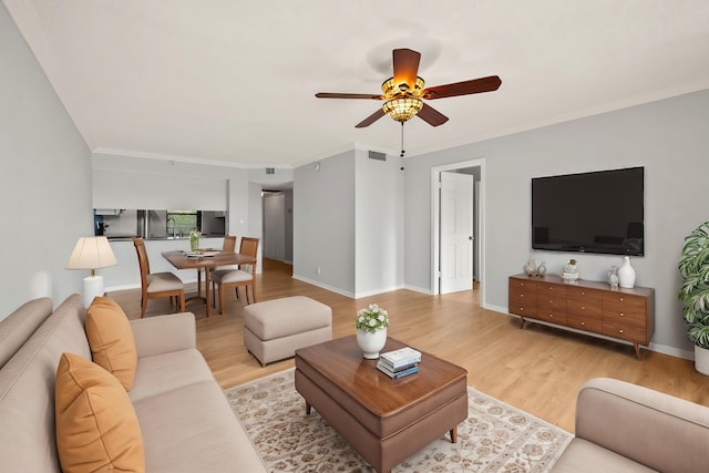 living room with light wood-type flooring, ceiling fan, and crown molding