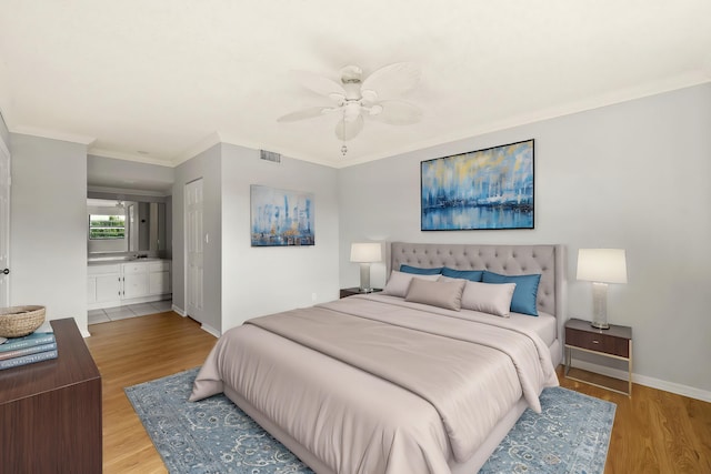 bedroom with light hardwood / wood-style floors, ceiling fan, crown molding, and ensuite bathroom