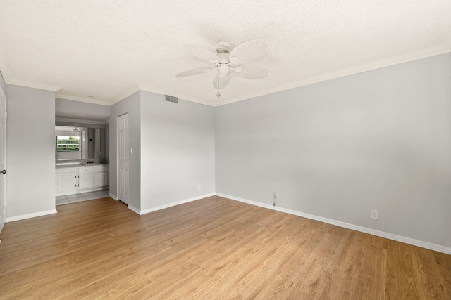 spare room with a textured ceiling, ceiling fan, light hardwood / wood-style floors, and crown molding