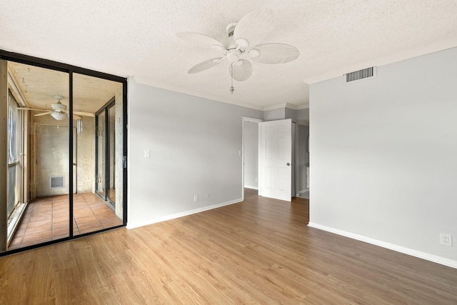 empty room with a textured ceiling, hardwood / wood-style flooring, ceiling fan, and ornamental molding