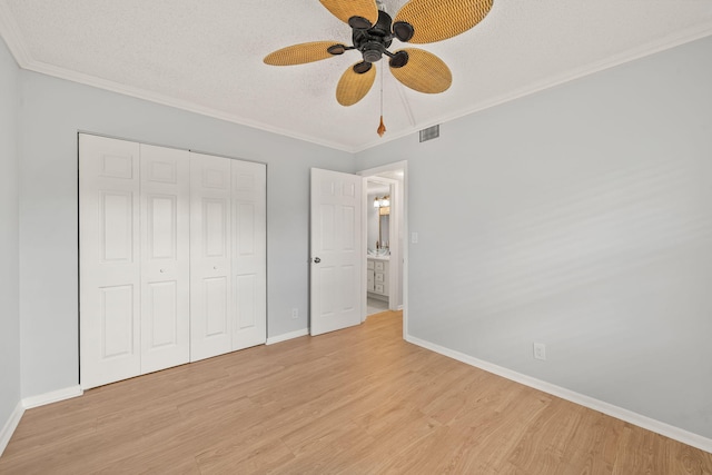 unfurnished bedroom with light wood-type flooring, a closet, ceiling fan, and crown molding