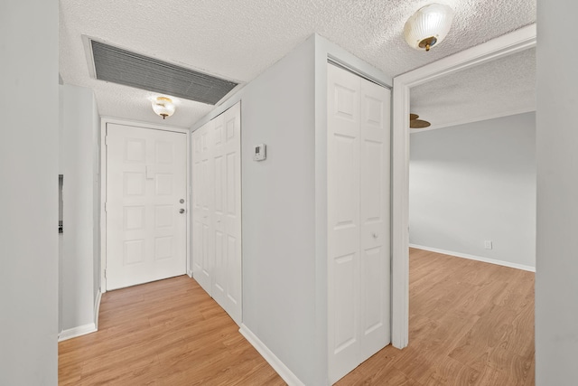 corridor with light hardwood / wood-style floors and a textured ceiling