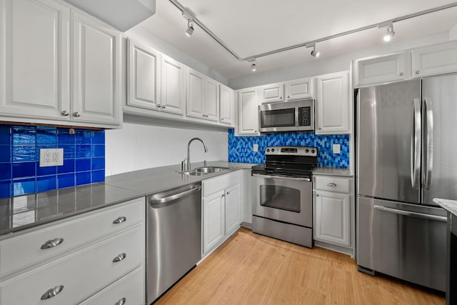 kitchen with white cabinets, sink, decorative backsplash, appliances with stainless steel finishes, and light hardwood / wood-style floors