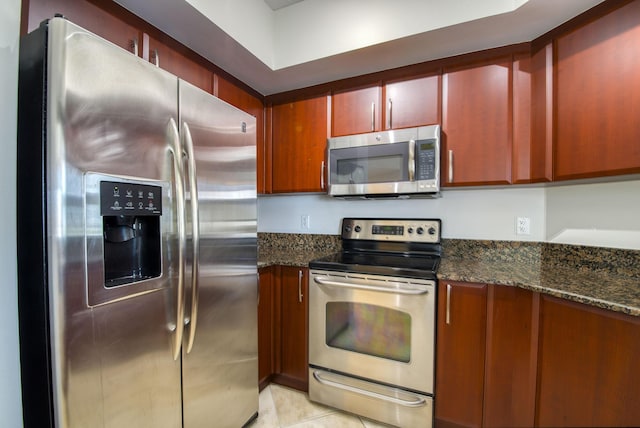 kitchen featuring dark stone countertops, light tile patterned floors, and appliances with stainless steel finishes