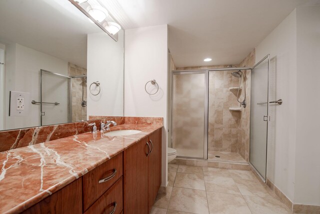 bathroom featuring tile patterned flooring, vanity, toilet, and an enclosed shower