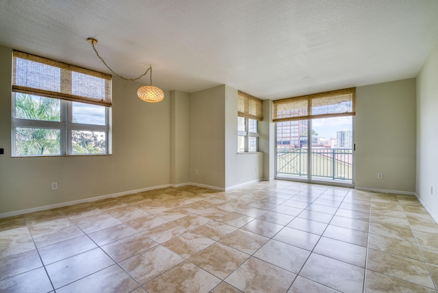 empty room featuring light tile patterned floors, a textured ceiling, and a healthy amount of sunlight